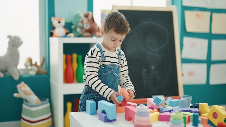 Photo gratuit adorable garçon caucasien jouant avec des blocs de construction à la maternelle