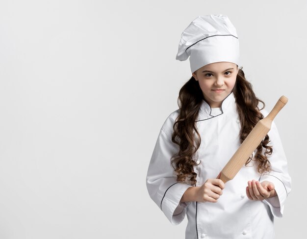 Adorable jeune chef tenant un rouleau à pâtisserie