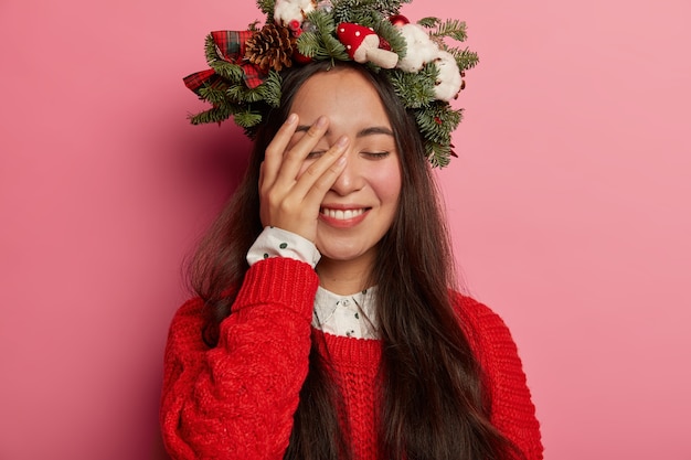 Adorable jeune femme sourit agréablement portant une couronne de fête sur la tête