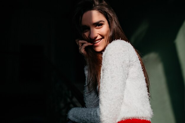 Adorable jeune femme en tenue blanche élégante en riant à la caméra