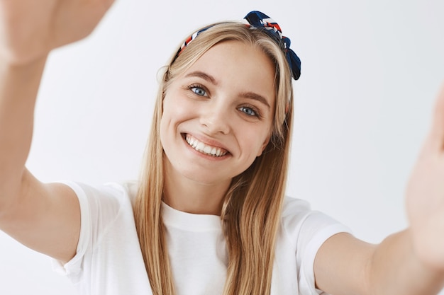Photo gratuite adorable jeune fille blonde posant contre le mur blanc