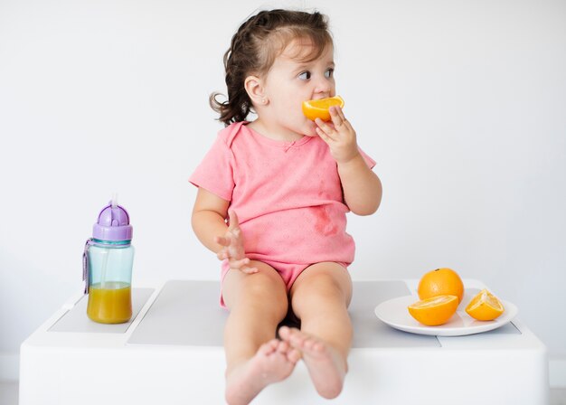 Adorable jeune fille mange une orange