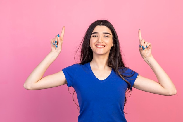 Adorable jeune fille pointant ses doigts vers le haut et souriant Photo de haute qualité