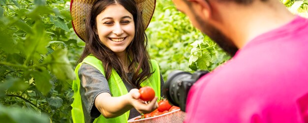 Adorable jeune fille souriant à la caméra et tenant des tomates