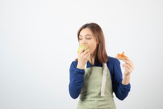 Adorable jeune fille en tablier mangeant une pomme verte au lieu de pizza.