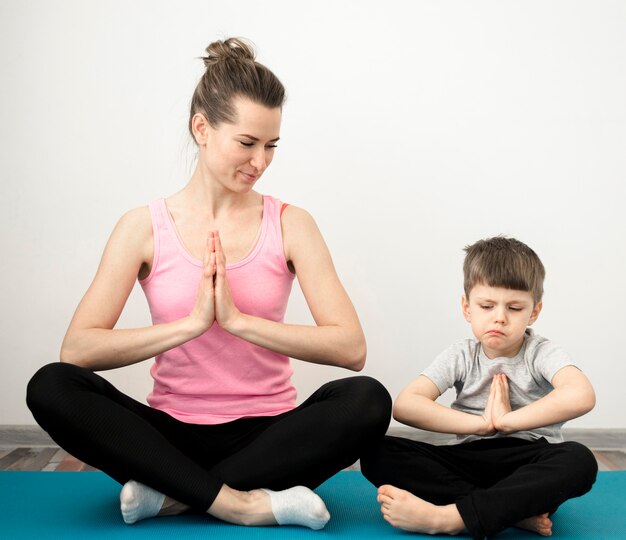 Adorable jeune garçon pratiquant le yoga avec la mère