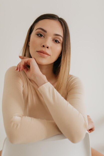 Adorable jolie femme aux yeux bruns maquillage nu et cheveux clairs pose devant la caméra pendant la séance photo