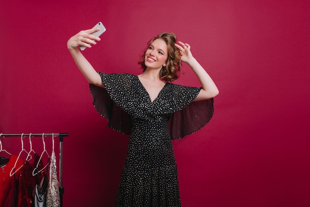 Adorable modèle féminin avec beau sourire faisant selfie dans le vestiaire