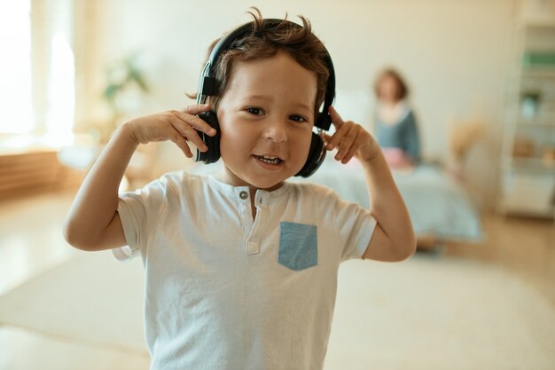 Adorable petit garçon doux portant des écouteurs sans fil, écoutant de la musique