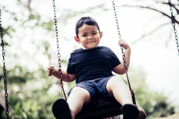 Adorable petit garçon s&#39;amuser sur une balançoire en plein air