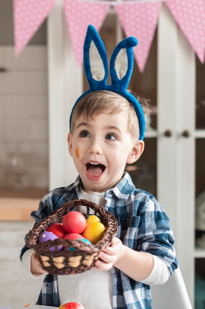 Adorable petit garçon tenant un panier avec des oeufs de Pâques