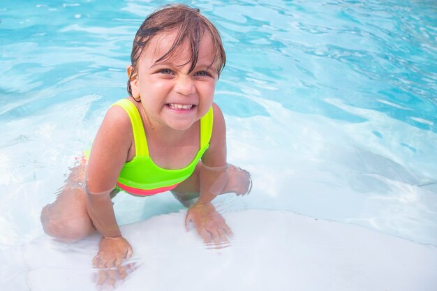 Adorable petite fille caucasienne dans la piscine en été petite fille profitant de la piscine de l'hôtel en voyage de vacances
