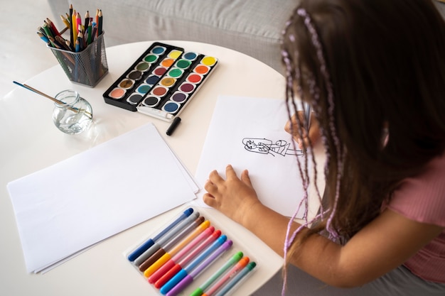 Adorable petite fille dessinant sur papier à la maison