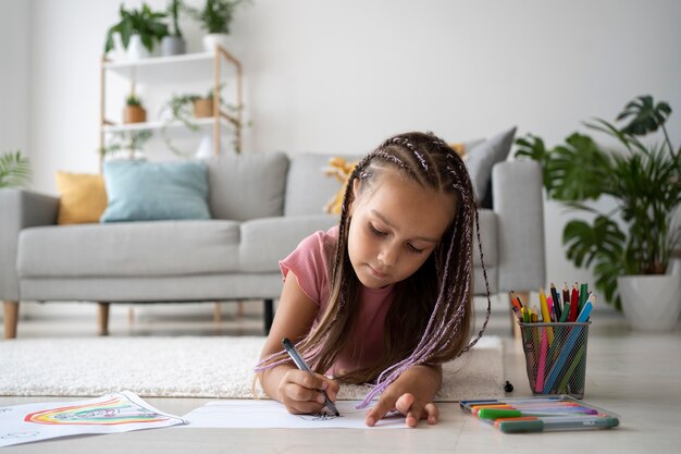 Adorable petite fille dessinant sur papier à la maison