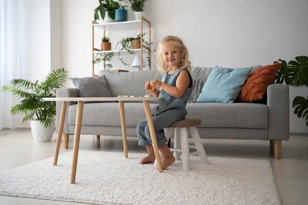 Adorable petite fille fabriquant des accessoires avec différentes boules colorées