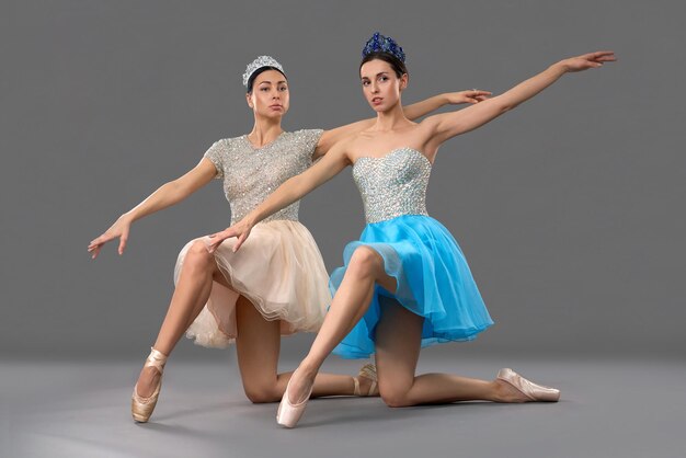 Adorables danseurs de ballet assis sur les genoux et levant la main