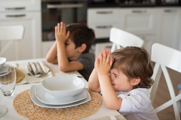 Adorables enfants priant à la maison