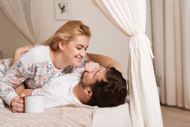 Adorables jeunes amoureux jouant ensemble au lit