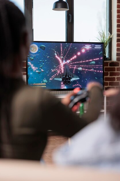 Adulte afro-américain jouant à des jeux vidéo avec console de télévision, profitant d'activités de loisirs avec des amis à la maison. Personne s'amusant avec le jeu de tir et la compétition, les jeux télévisés.