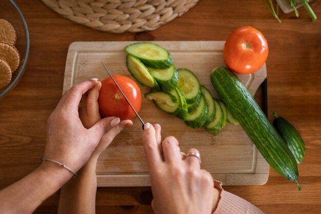 Adulte apprenant à un enfant à couper des aliments avec un couteau