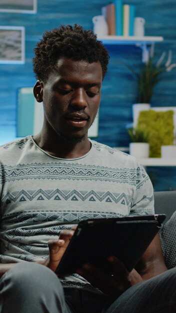 Adulte tenant une tablette numérique et tapant sur l'écran tactile pour le travail à distance en ligne. Homme d'affaires utilisant un appareil moderne travaillant à domicile pour un projet d'entreprise. Entrepreneur avec la technologie