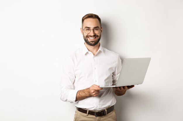Affaires. Homme d'affaires prospère travaillant avec un ordinateur portable, utilisant un ordinateur et souriant, debout