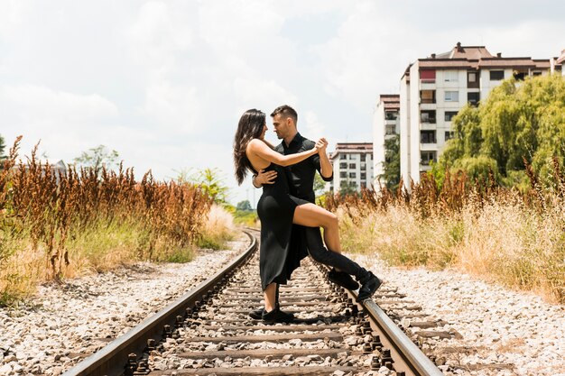 Affectueux jeune couple dansant sur le chemin de fer