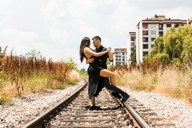 Affectueux jeune couple dansant sur le chemin de fer