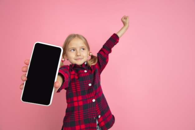 Affichage d'un écran vide. Portrait de petite fille caucasienne sur mur rose.