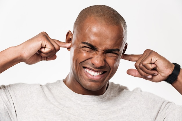 Photo gratuite un africain mécontent ferme les oreilles d'un bruit.