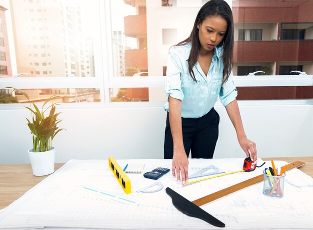 Afro-américaine avec règle près de plan sur table avec des équipements