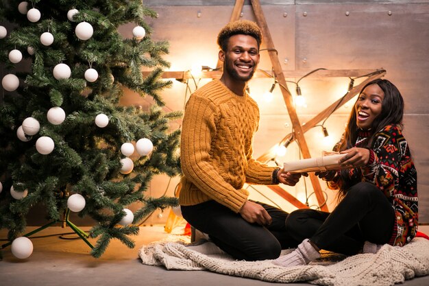 Afro couple américain assis près de l&#39;arbre de Noël