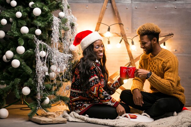 Afro couple américain, boire du café par le sapin de Noël