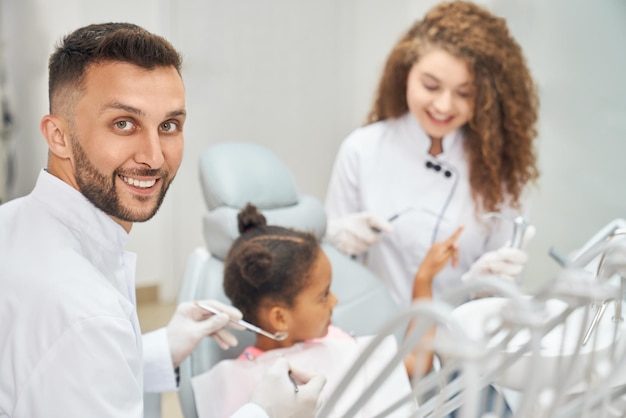 Afro girl en fauteuil dentaire avec dentiste et assistant autour