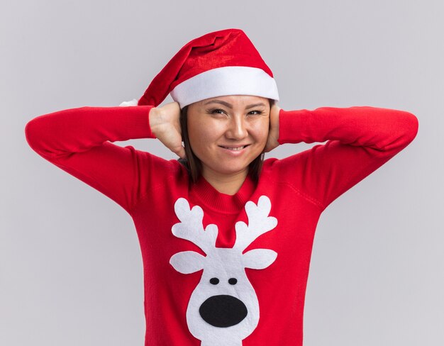 Agacé jeune fille asiatique portant chapeau de Noël avec des oreilles couvertes de pull isolé sur fond blanc