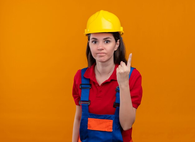 Agacé jeune fille constructeur montre un geste du doigt sur fond orange isolé avec copie espace