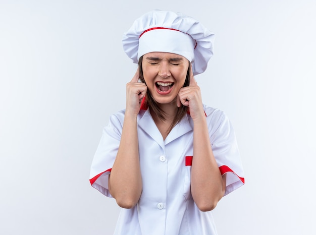 Agacé avec les yeux fermés jeune femme cuisinier portant des oreilles couvertes d'uniforme de chef isolé sur fond blanc