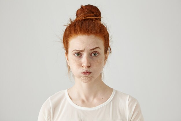 Agacée, irritée, jeune femme rousse avec des taches de rousseur sur les joues, fronçant les sourcils, se sentant frustrée par quelque chose. Expressions faciales humaines, émotions et sentiments. Concept de fatigue ou d'ennui