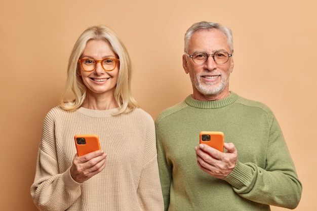 L'âge des gens et le concept technologique. Portrait de femme d'âge moyen et homme détiennent des smartphones,