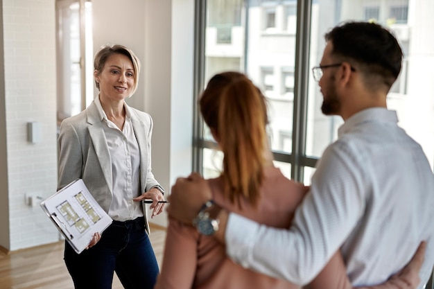 Photo gratuite agent immobilier féminin communiquant avec un couple tout en leur montrant un nouvel appartement