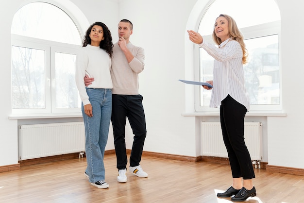 Photo gratuite agent immobilier féminin montrant une nouvelle maison de jeune couple