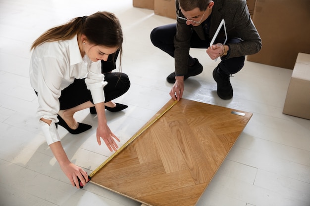 Photo gratuite agent immobilier féminin montrant la nouvelle maison à un jeune homme après une discussion sur les plans de la maison, le déménagement, le nouveau concept de maison