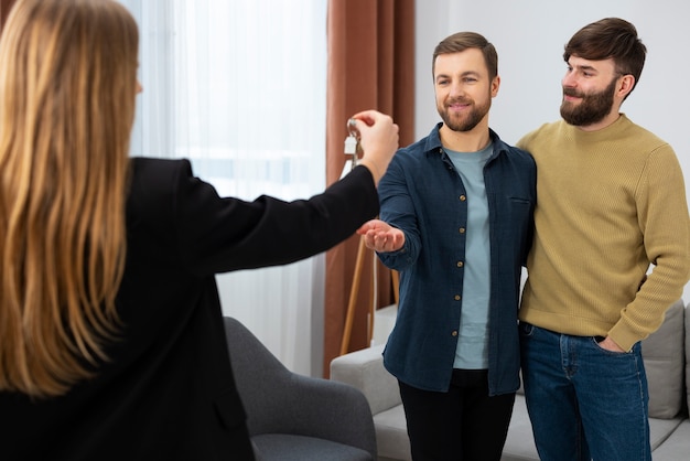 Agent immobilier féminin parlant affaires et montrant la maison à un couple gay