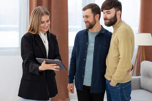 Photo gratuite agent immobilier féminin parlant affaires et montrant la maison à un couple gay