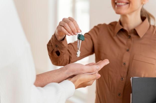 Agent immobilier féminin Smiley remettant au couple les clés de leur nouvelle maison