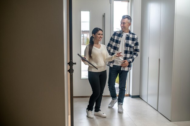 Agent immobilier femme souriante montrant un homme d'âge moyen intéressé joyeux sa nouvelle maison pendant la journée