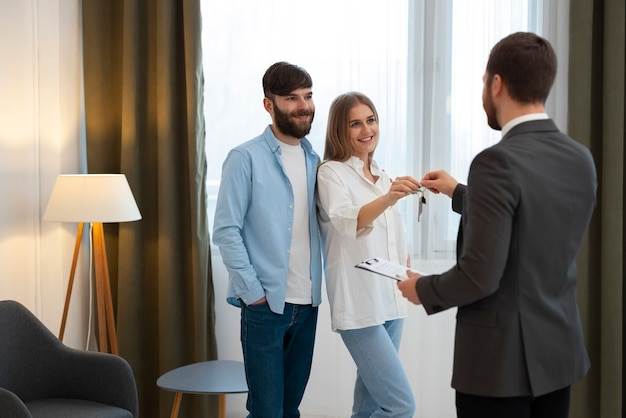 Agent immobilier masculin faisant des affaires et montrant la maison à un couple d'acheteurs potentiels