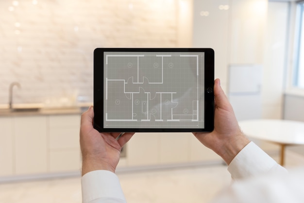 Agent immobilier masculin tenant une tablette avec plan de maison