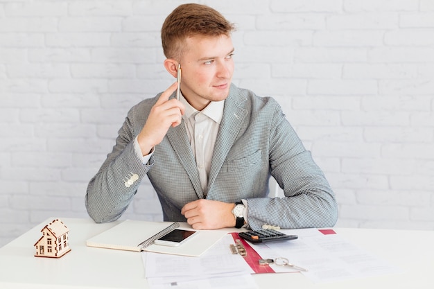 Agent immobilier pensif assis au bureau