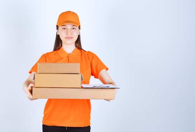 Agent de service féminin en code vestimentaire de couleur orange livrant plusieurs boîtes en carton